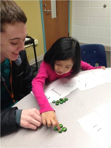 Jacob Kelleher, Junior, helps child, Say Ray, with some work. 