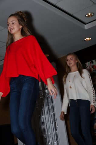 Emma Ohrenstein (junior, red sweater) and Sydney Melms (sophomore, white sweater) strut down the runway. 