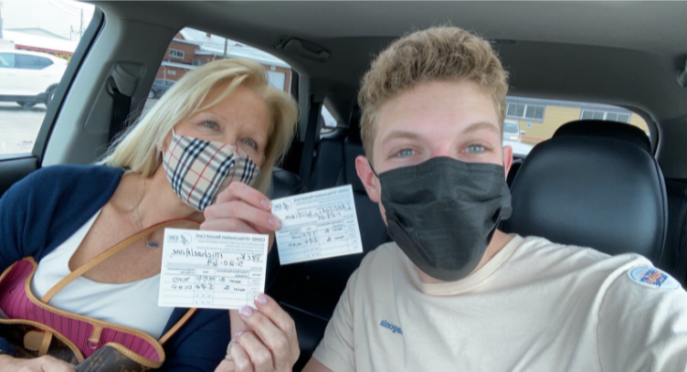 Editor and Writer, Will Lanciloti, holding up his vaccination card along with his mom.
