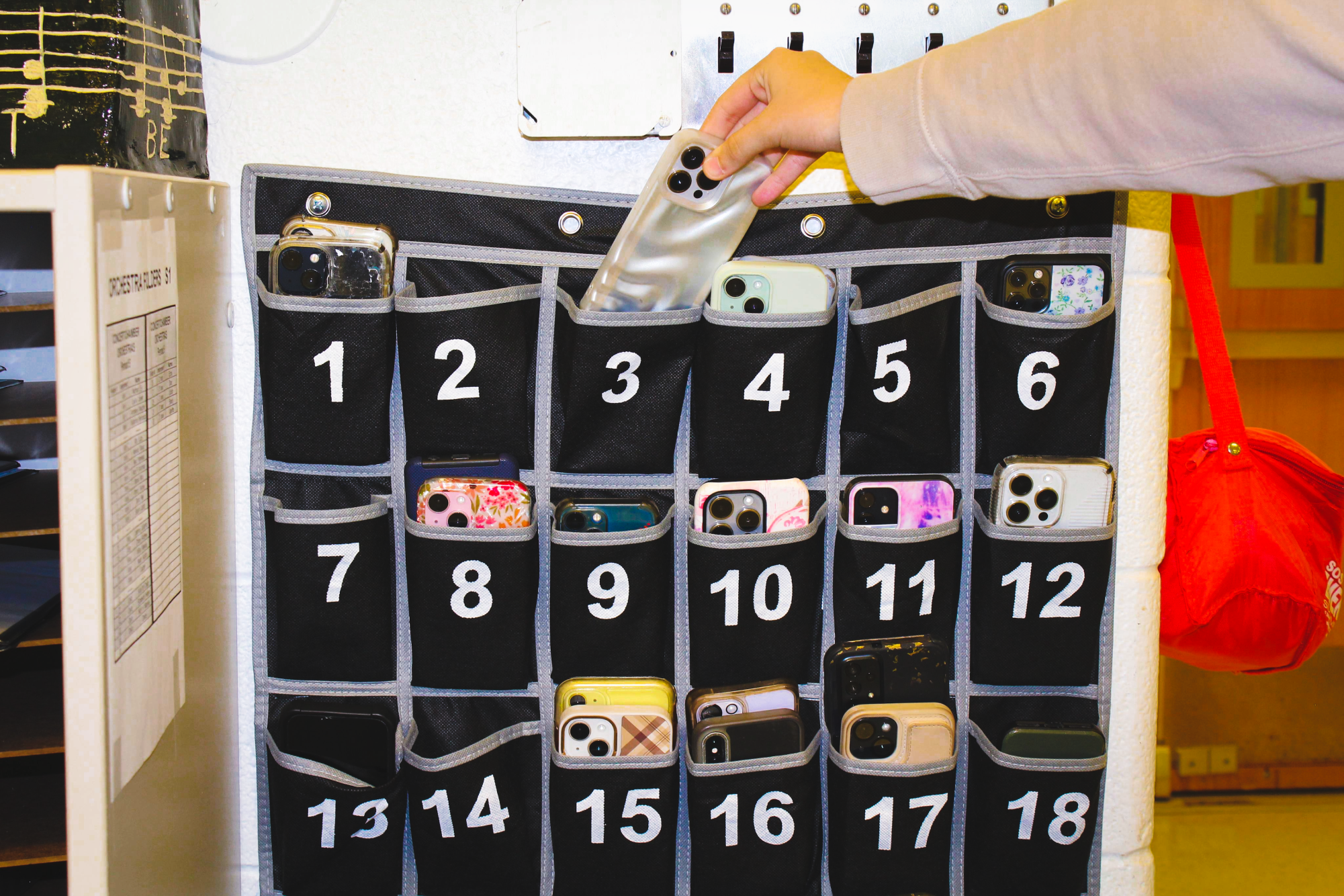 Student placing phone in phone pouch before class.